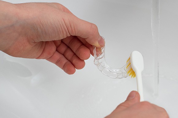 Closeup of patient cleaning clear aligner