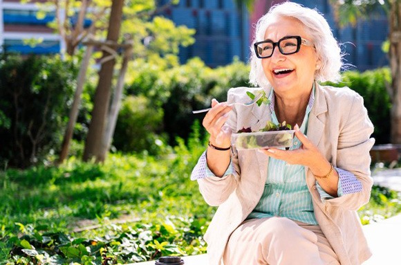 Lady smiles while eating salad