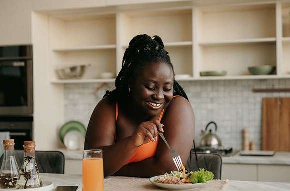 Woman smiling while enjoying meal at home