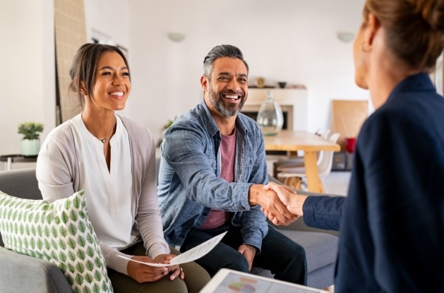 Couple sitting on couch with the man shaking hands with person sitting across from him