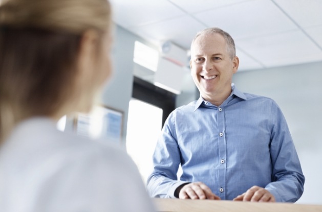 Man talking to dental team member at front desk