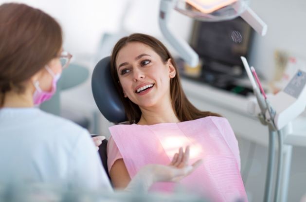 Woman with long brown hair talking to dentist