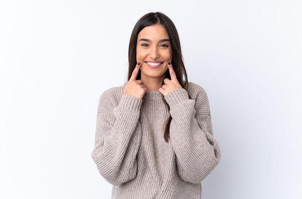 Happy young woman pointing at her smile