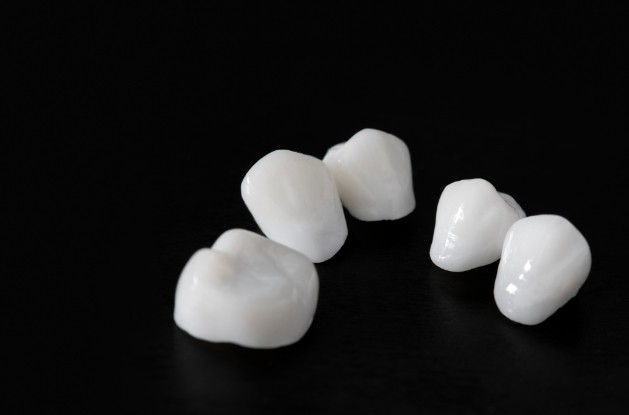 Five ceramic dental crowns against black background