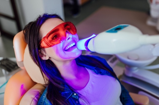 Woman receiving professional teeth whitening in dental office