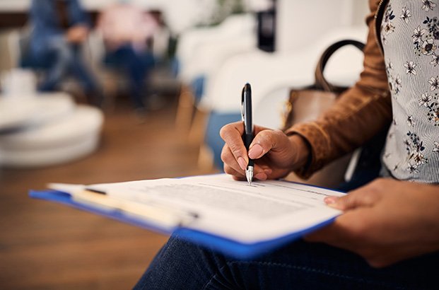 Person filling out paperwork on clipboard
