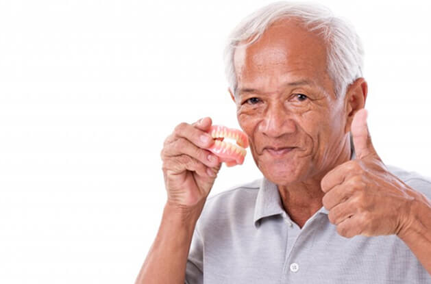 smiling man holding dentures