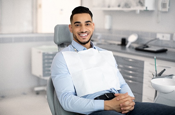 Dentist, patient, and dental assistant smiling and giving thumbs up