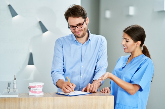 Dental team member showing a patient where to sign on paper