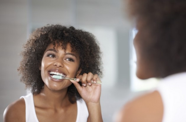 Woman smiling while brushing her teeth