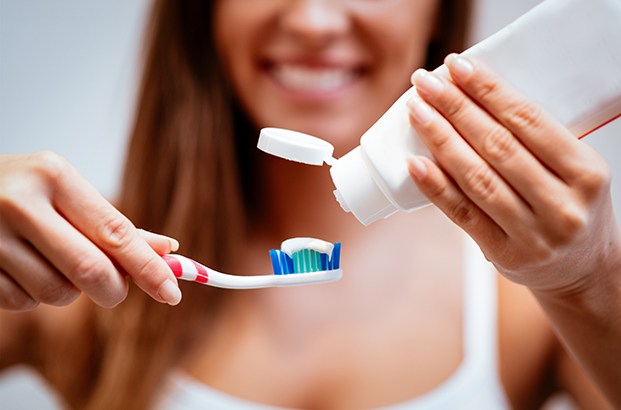 Closeup of woman squeezing toothpaste onto toothbrush. 