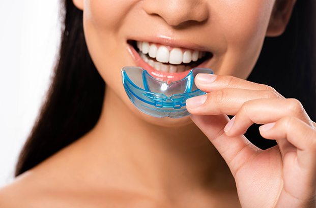 Nose-to-neck view of woman inserting light blue mouthguard