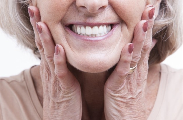Smiling senior woman touching her face