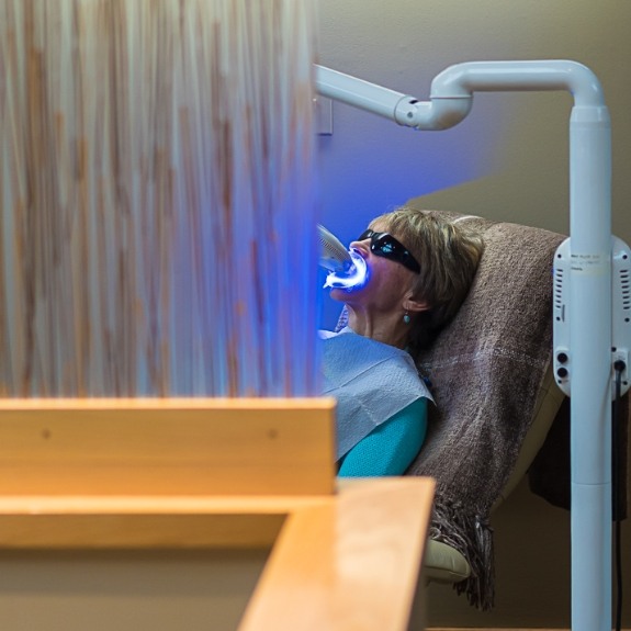 Woman getting teeth whitening in dental office