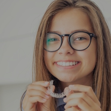 Young girl holding Invisalign aligner