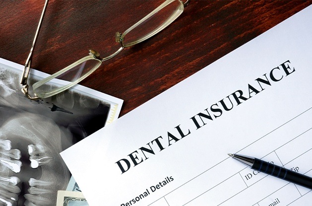 Dental insurance paperwork on dark wood table