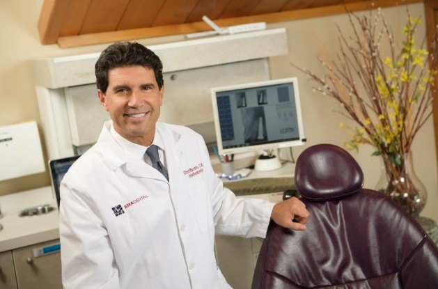 Doctor Mariano smiling by dental exam chair