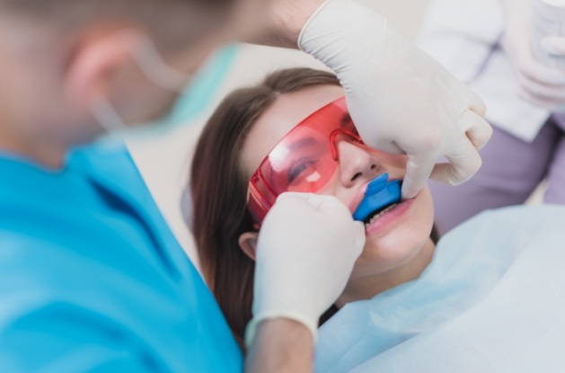 Young woman in dental chair with fluoride tray over her teeth