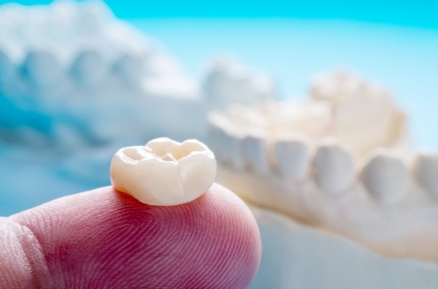 Close up of person holding dental crown on their finger