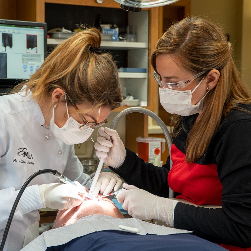 Dentist and assistant focusing on treating a dental patient