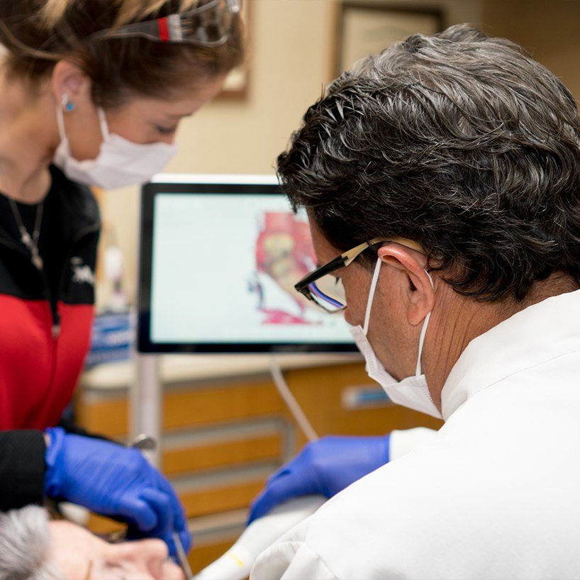 View of dentist from behind treating a dental patient