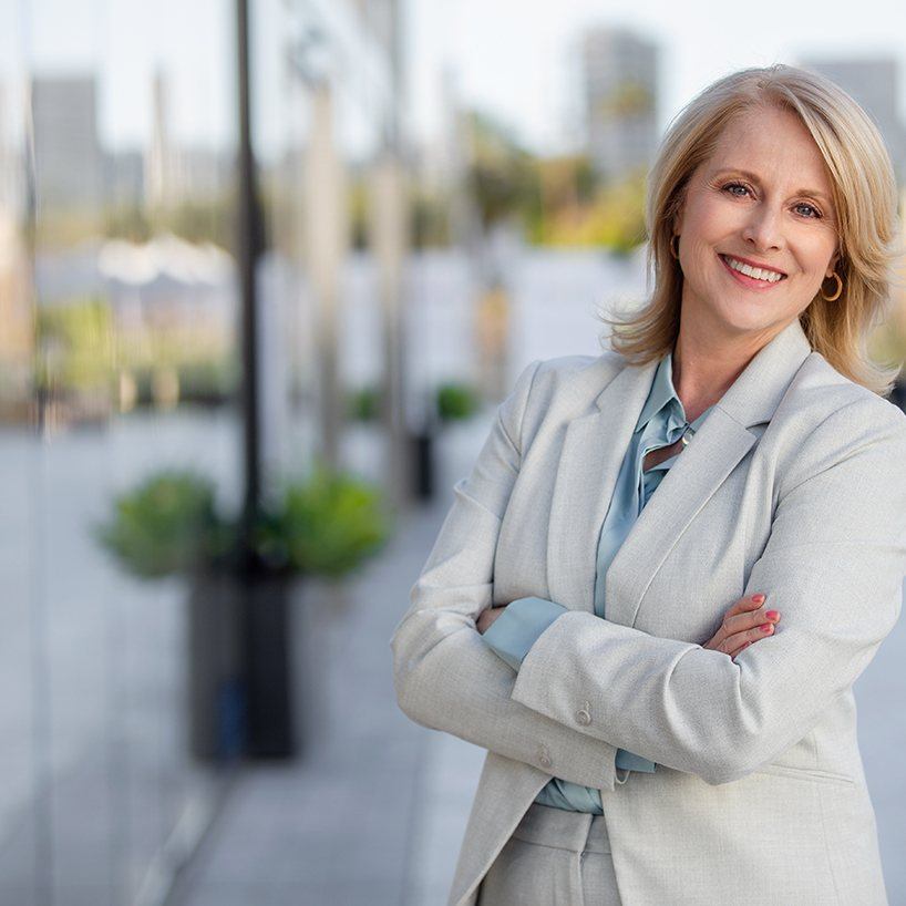 Woman in business attire smiling while crossing her arms