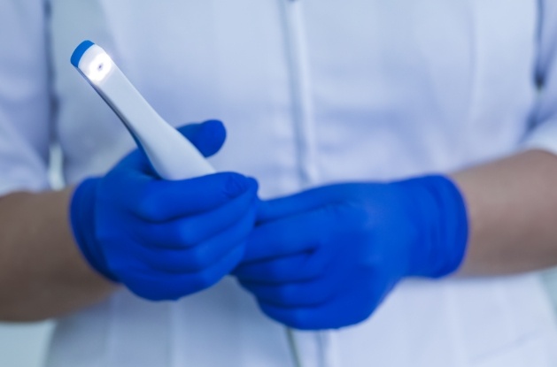 Dental team member holding thin white intraoral camera