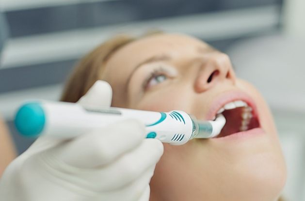 Dentist holding a cavity detection device inside mouth of patient