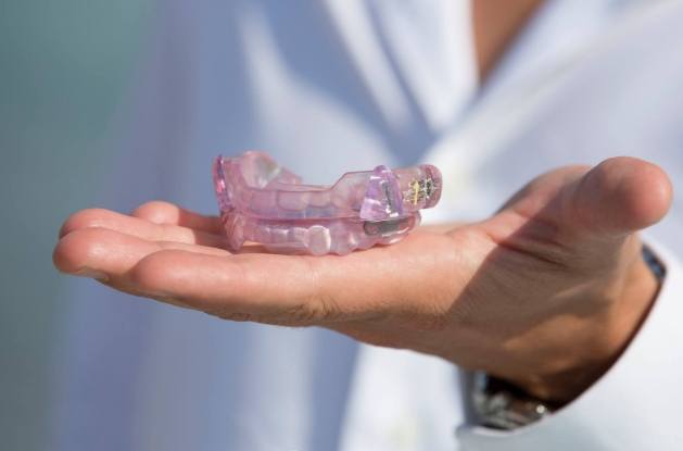 Dentist holding light purple occlusal splint in their hands