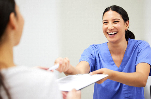 detal assistant smiling while handing patient form