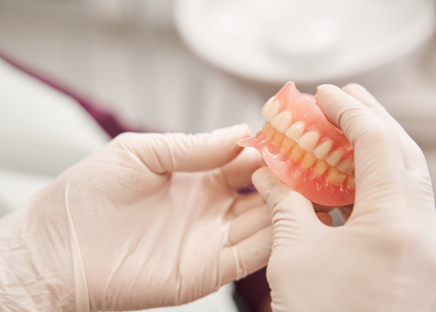 Close-up of dentures in dentists' hands