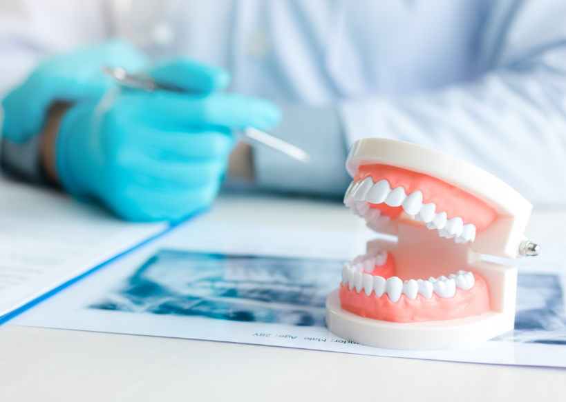Dentures on desk with dentist's hand in background